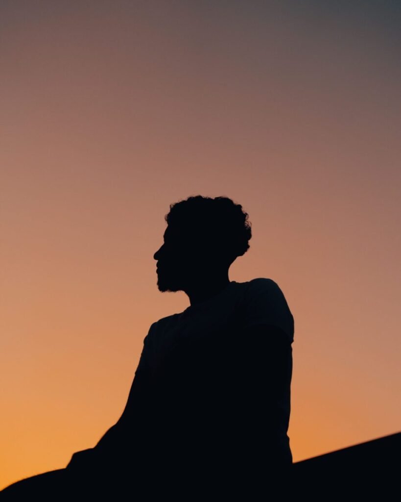 A serene silhouette of a man against a vibrant sunset in Andenne, Belgium, capturing a moment of reflection.